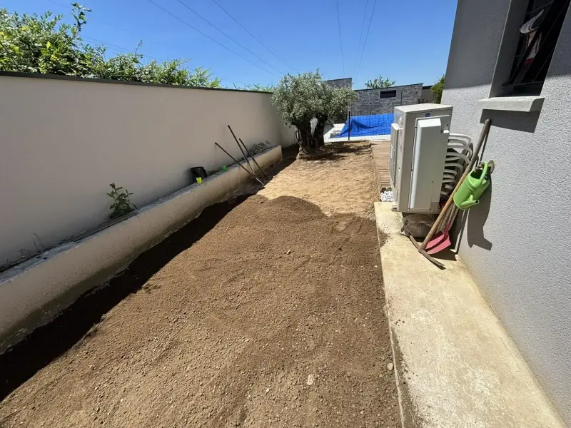 Bande de terre nivelée et affinée le long d’une maison, prête à recevoir un gazon